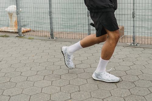 Free Close-up of a man running outdoors in white sneakers by a waterfront. Stock Photo