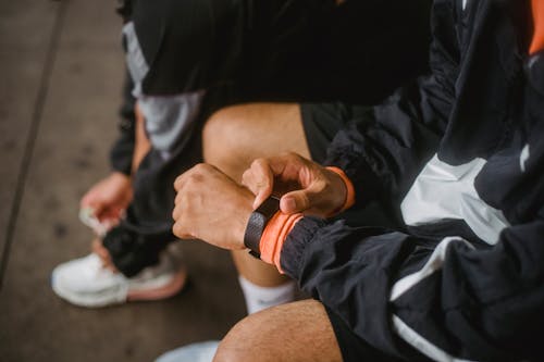 Free Close-up of a man in athletic wear adjusting a smartwatch, showcasing fitness and technology integration. Stock Photo