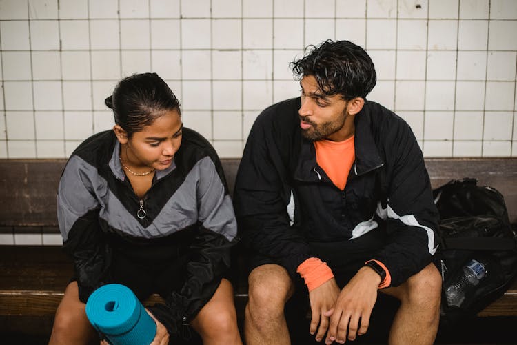 Two Young Sport People Resting After Fitness Exercises In Changing Room