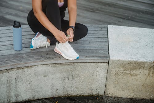 Photo of a Woman in Activewear Tying Her White Shoes