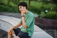 一个穿着休闲运动服的男人坐在公园的长椅上打电话