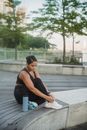Woman in Black Tank Top Sitting on Gray Concrete Bench