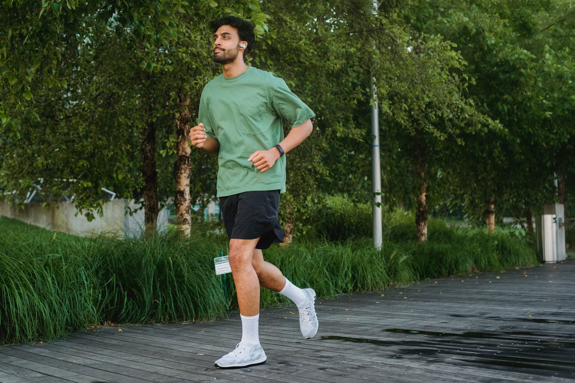 Free Man in Green T-shirt and Black Shorts Running on the Park Stock Photo