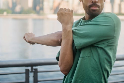 Man in Green T-shirt Stretching His Arms