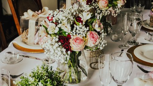 Free An elegant table setting featuring a vibrant bouquet of roses and delicate glassware, perfect for special occasions. Stock Photo