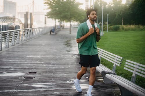 Man in Green Crew Neck T-shirt Running on Boardwalk