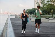 两个朋友在河边的木板路上散步，以促进健身和健康的生活方式