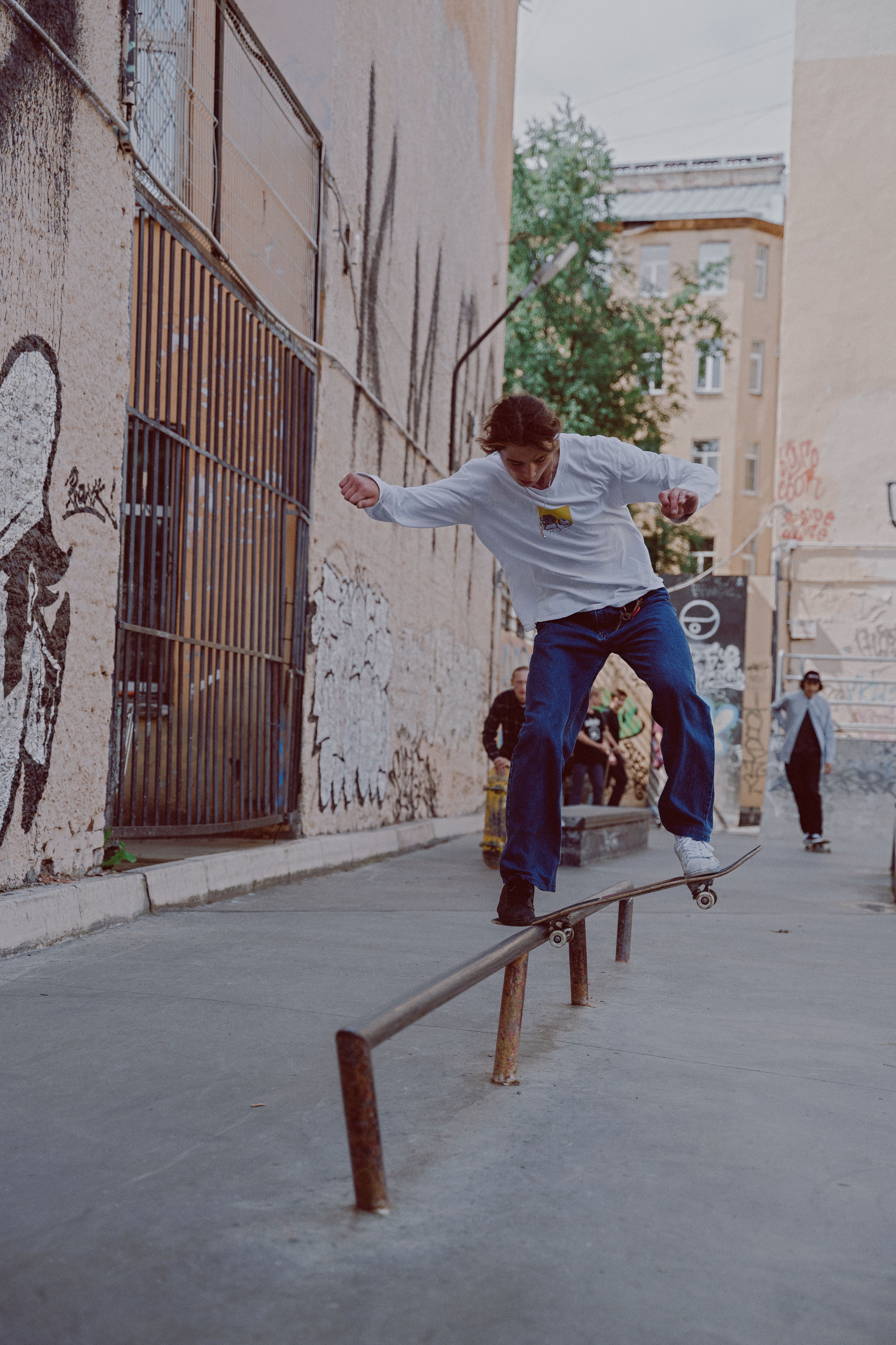 Skilled skateboarder in an urban setting balancing on a rail with graffiti in the background.