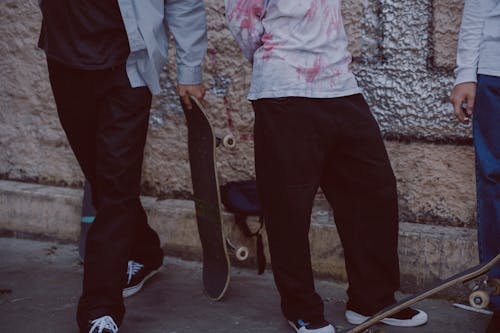蓝色的裤子和粉红色的衬衫，拿着黑色的滑板的人
