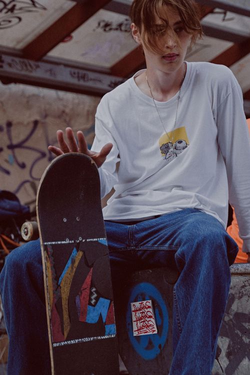Free Close-up of a skateboarder in casual wear sitting on a graffiti-covered ledge. Stock Photo