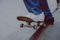 Person in Blue Denim Jeans Riding Brown Wooden Skateboard