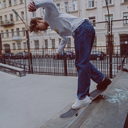 Free Man in White Long Sleeve Shirt and Blue Denim Jeans Jumping on Gray Concrete Floor during Stock Photo