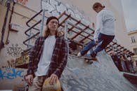 两名滑板手在一个涂满涂鸦的滑板公园里，其中一人正在坡道上滑行