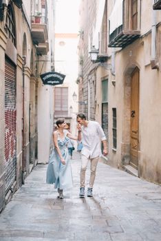 一对夫妇手牵手，在风景如画的巴塞罗那街道上微笑着享受浪漫的散步