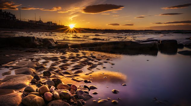 Stunning sunset over a rocky seashore, capturing reflections and warm vibrant tones.