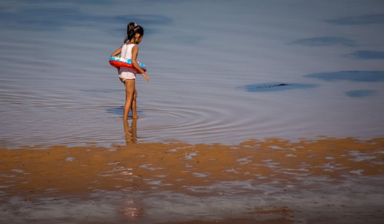 Kid Wearing A Floatie Walking On Seashore