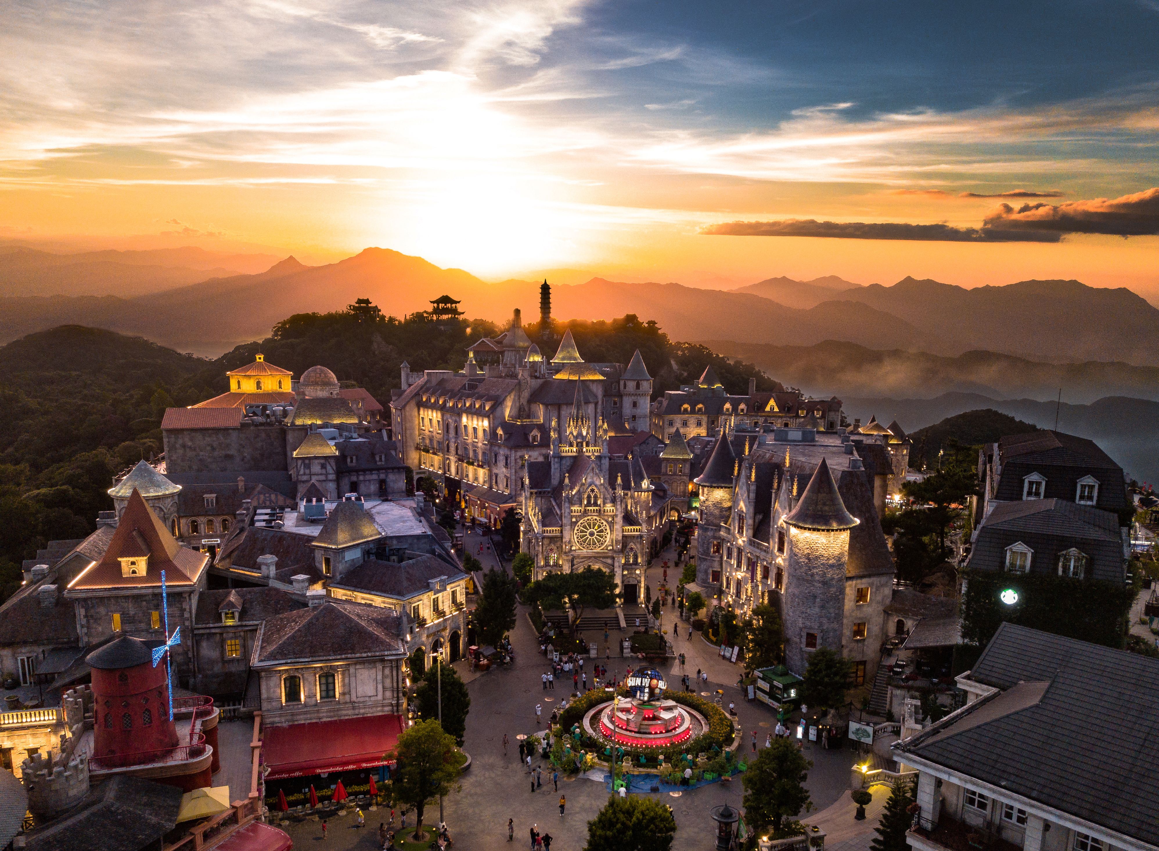 Aerial view of a European-style town with stunning architecture and mountains at sunset.