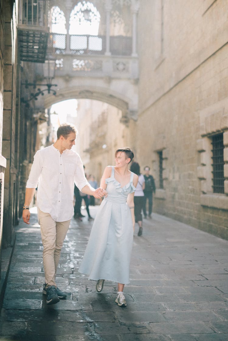 A Couple Walking On The Street While Holding Hands