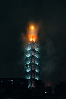 夜晚，台北101的迷人景色被云层和灯光环绕，展现出建筑的现代感