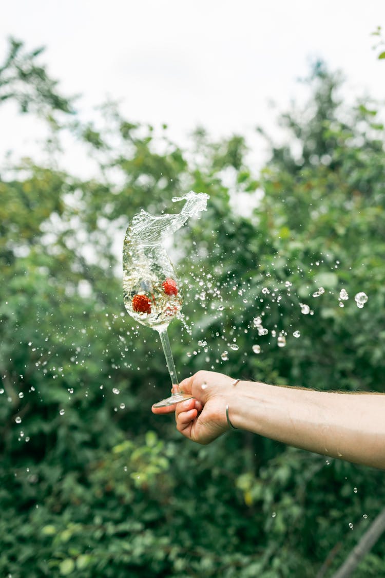 Person Holding Wine Glass Splashing Water