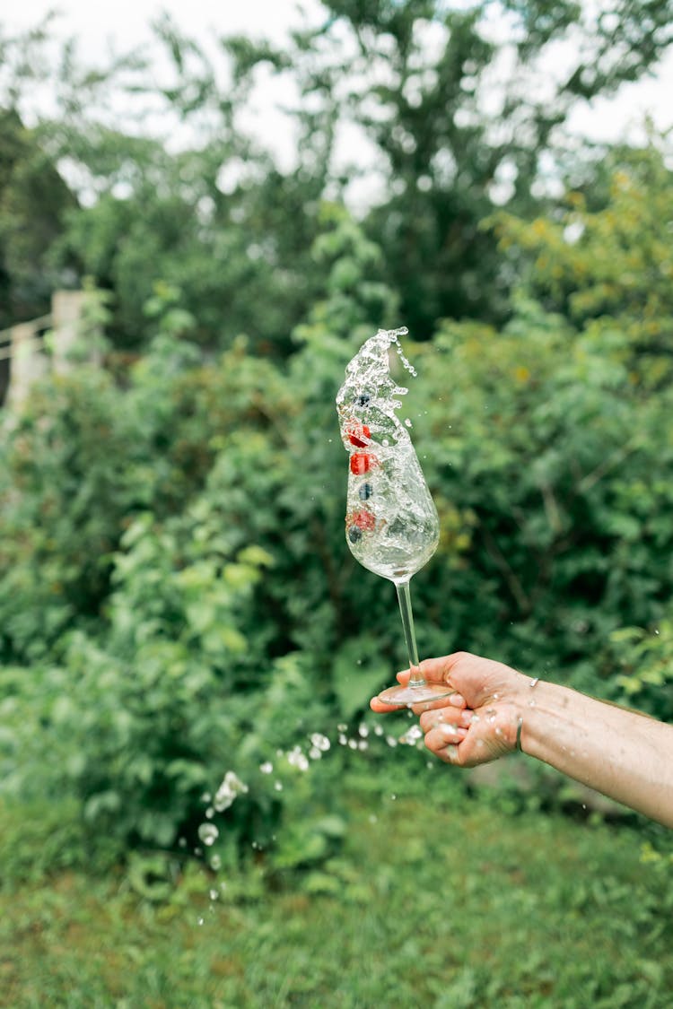 Person Holding Wine Glass Splashing Water