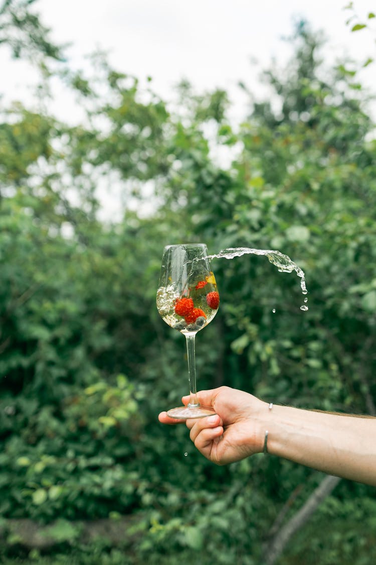 Person Holding Wine Glass Splashing Water