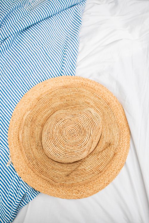 Free A top view of a straw hat lying on a blue and white striped towel, creating a summer vibe. Stock Photo