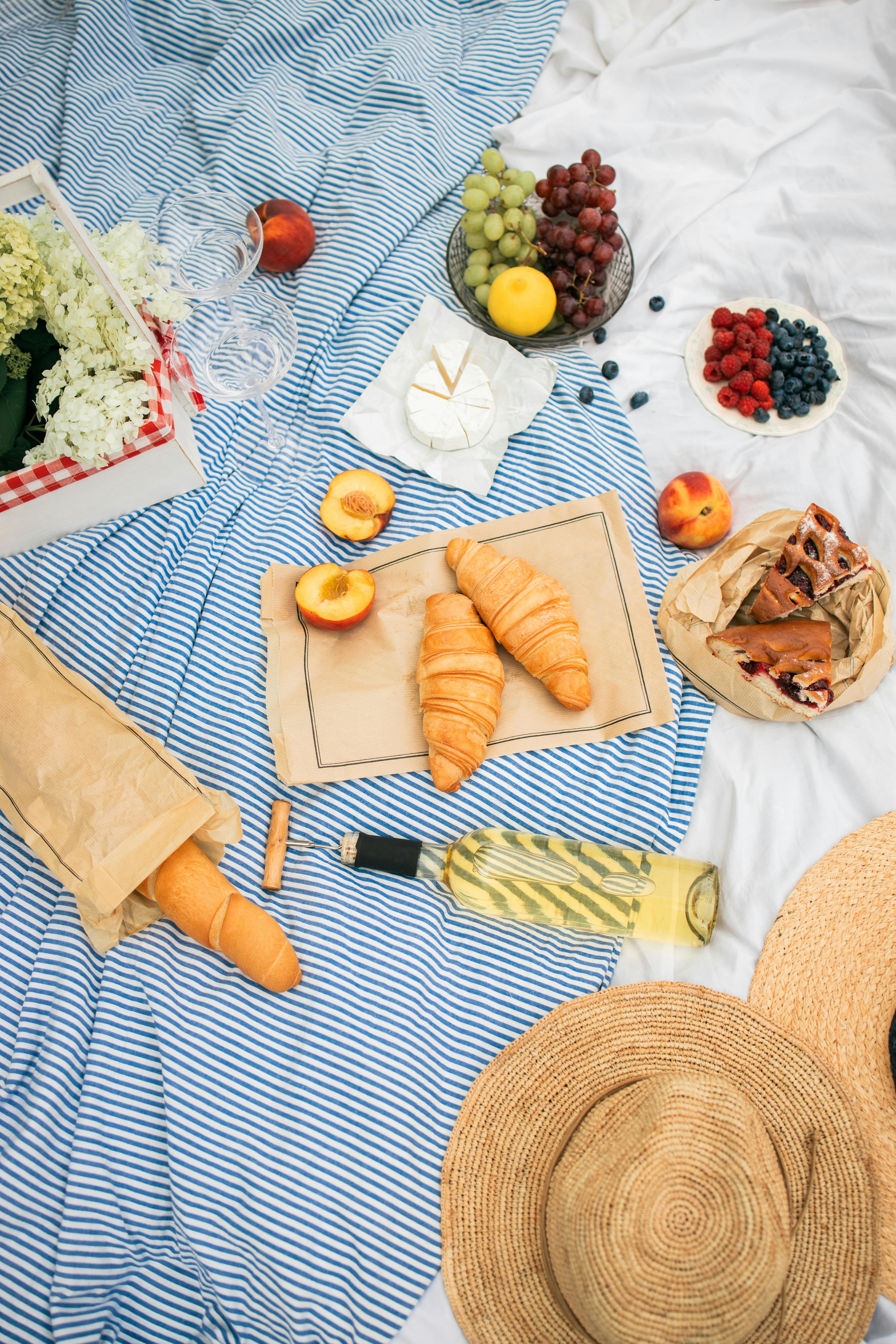 food and white wine on a picnic blanket