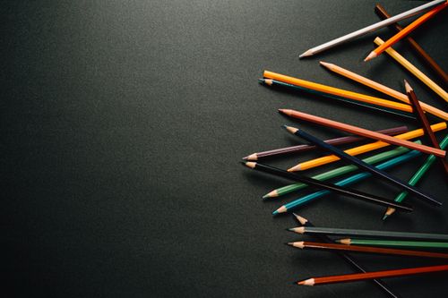 Free From above of colourful pencils scattered on dark surface in contemporary dark studio while placed on each other on black background Stock Photo