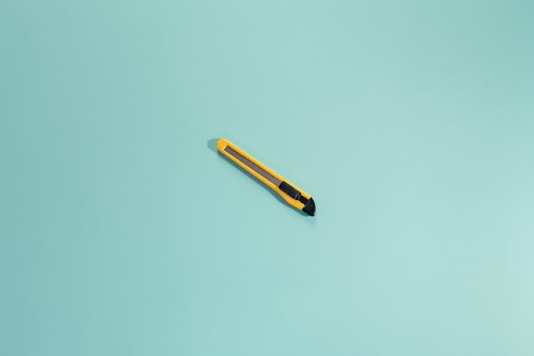 Stationery Knife On Colored Surface