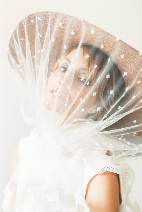 Женщина в белом свадебном платье в коричневой шляпе от солнца