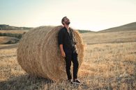 Man in Black Jacket Standing on Brown Grass Field