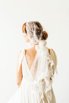 一位身着婚纱、头戴花边面纱的妇女背影，凸显出新娘的优雅