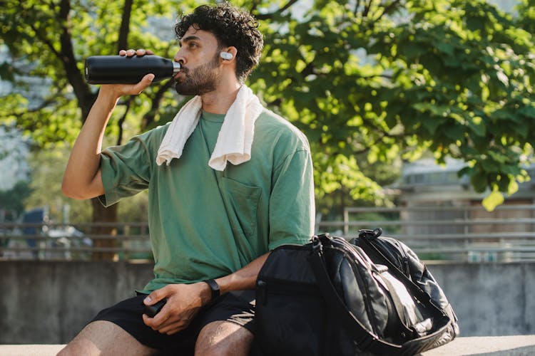 Man Drinking From A Bottle After An Exercise