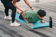 Woman in Green Shirt and Black Leggings Lying on Blue Yoga Mat