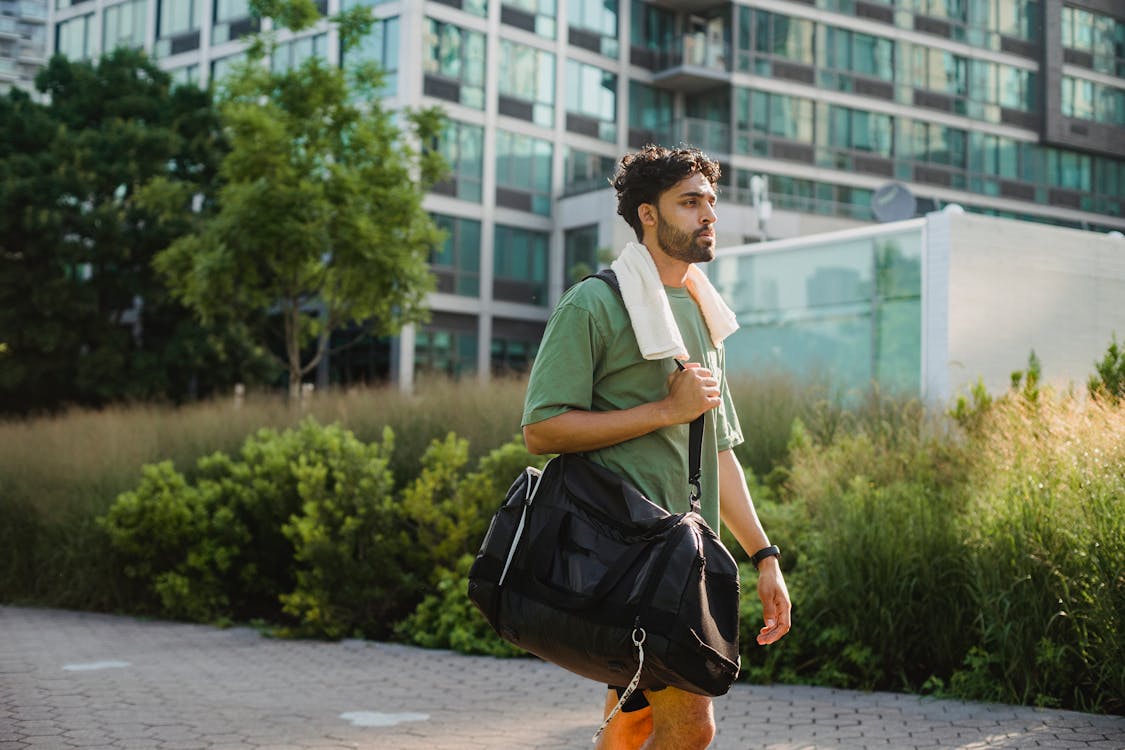 Man with Sports Bag Walking on City Street · Free Stock Photo