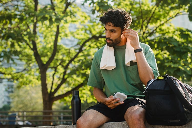 Man Sitting In Park With Towel Around Shoulde