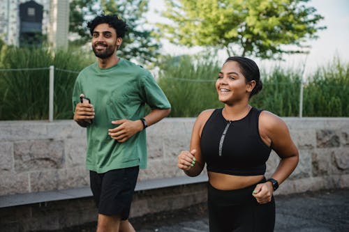 Free Man and Woman Smiling While Jogging Together Stock Photo