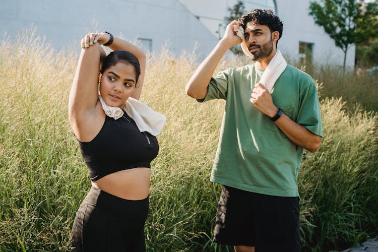 Woman And Man Stretching After Exercising Outdoors 