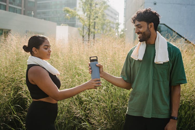 Man Handing A Woman A Water Bottle After Exercising 