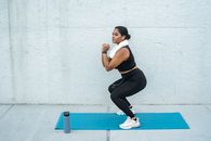 Woman in Black and White Tank Top and Black Leggings Sitting on Blue and White Skateboard