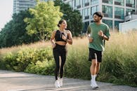 2 Women in Black Tank Top and Black Leggings Running on Gray Concrete Pathway