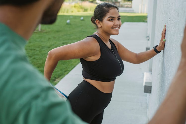 Smiling Woman In Sportswear Exercising Outside