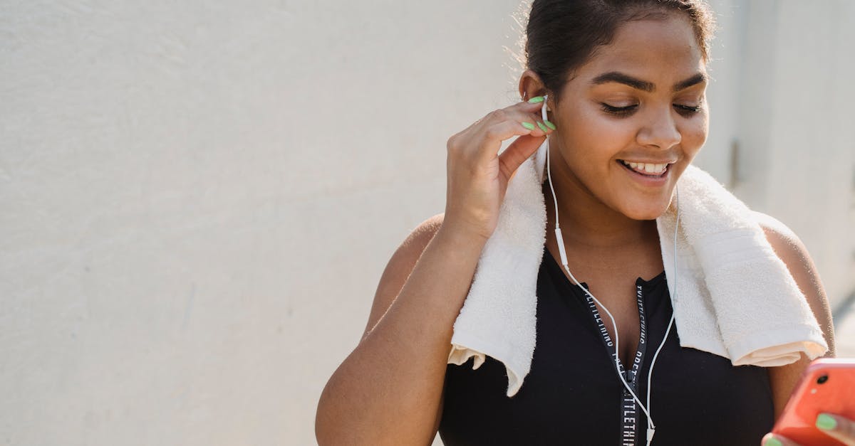 Woman in Sports Clothing Putting Earphones in and Smiling 