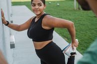 Woman in Black Sports Bra and Black Leggings Holding White and Blue Plastic Pack