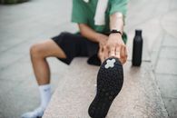 穿着运动服的年轻人带着毛巾和水瓶，在户外伸展身体