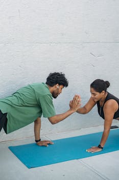 A man and woman performing a plank workout with a high five outdoors.