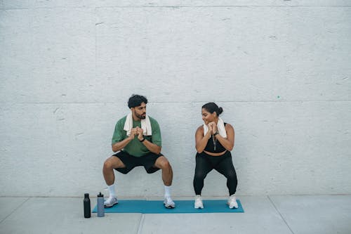 Free Man and Woman Doing Squats during a Workout Stock Photo