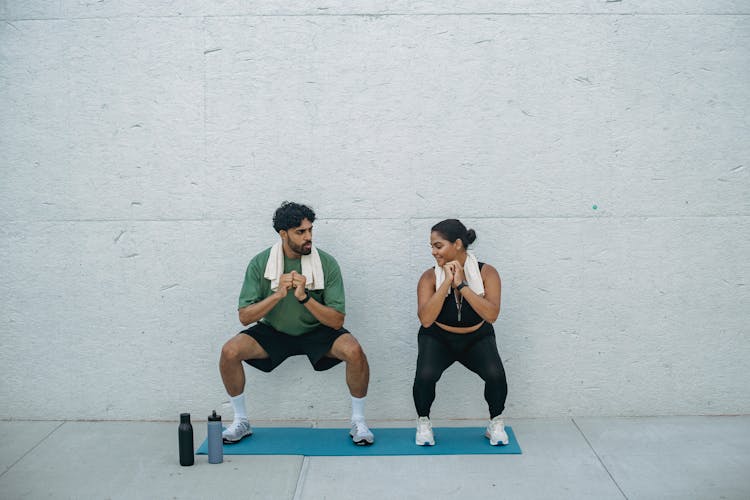 Man And Woman Doing Squats During A Workout