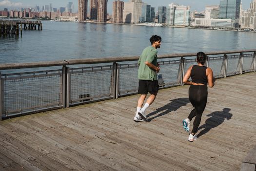 Two adults jogging on a pier, enjoying fitness and a healthy lifestyle by the waterfront.